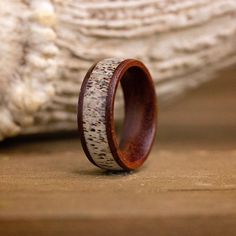 a wooden ring with antelope inlays sits on top of a piece of driftwood