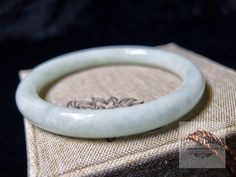 This 62mm inner diameter jade bangle bracelet features certified natural white jade, offering a timeless vintage style. Perfect as a meaningful gift for Christmas or New Year, it showcases the beauty of high-quality, authentic jade. Add a touch of elegance to any occasion with this exquisite piece of vintage jewelry, symbolizing luck and prosperity. Ideal for vintage jewelry lovers and those seeking a unique, thoughtful present for the holiday season. Size: 62mm Inner Diameter. The bangle is exquisitely crafted by skilled artisans, featuring intricate stone veins. This is a carefully selected piece just for you. NOTE: As it is made entirely from solid jadeite, please measure your wrist carefully before ordering. If you have any questions about choosing the right size, contact us through th Spiritual Jade Bangle For Gift, White Bangle For Gift, Jade Bangle Bracelet, Jade Bangle, White Jade, New Year Gift, Bracelet Vintage, Jewelry Lover, New Year Gifts