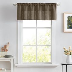 a window in a white room with a brown valance and flowers on the table