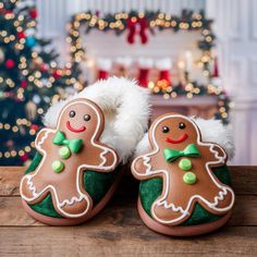 a pair of slippers decorated with gingerbreads on a wooden table in front of a christmas tree