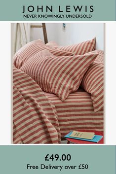 a bed with red and white striped sheets on it, next to a blue book