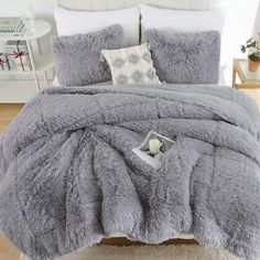 a bed with grey comforter and pillows on it