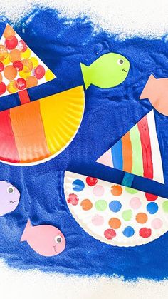 paper plate fish and other craft items on a blue background with watercolors in it