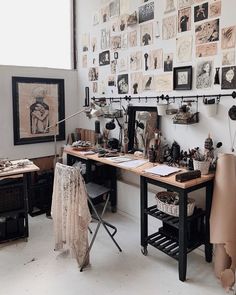 an art studio with lots of artwork on the wall and desks in front of it