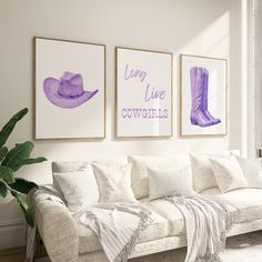 three purple and white pictures hang on the wall above a couch in a living room