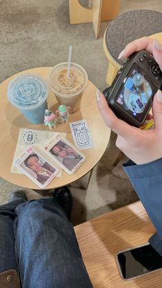 a person sitting at a table with a cell phone in their hand and some pictures on the table