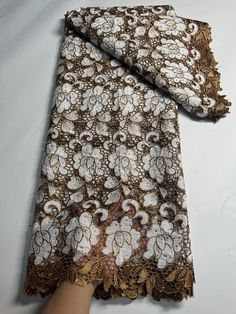 a person is holding onto a brown and white lace with flowers on the bottom of it