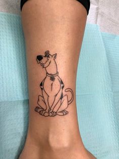 a small dog tattoo on the foot of a woman's right leg, which is decorated with black and white ink