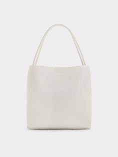 This item is part of our Online Exclusive selection, which consists of unique colourways and designs that are only available for purchase at CHARLESKEITH.COM. This product is made with at least 20% sustainable materials by weight. CHARLES & KEITH uses recycled, degradable, organic, and water-based materials in our eco-conscious collection. Made for work days, casual outings, and everything in-between, our Leia tote bag is loved for many reasons. With an immaculate and exquisite cream finish, this piece will certainly be hard to resist the moment you lay eyes on it. The ultra-smooth and minimalist exterior will makes it a delight to hold. Offering easy access to your belongings with the magnetic closure, it comes with a detachable pouch to keep your smaller items neat and organised. Minimalist Exterior, Black Saddle Bag, Chic Crossbody Bag, Brand Collaboration, Classic Handbags, Charts For Kids, White Tote, In Between, Charles Keith