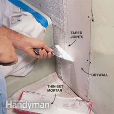 a man is painting the wall with paint and tape in his hand, next to a drywall