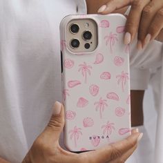 a woman holding an iphone case with pink palm trees on it