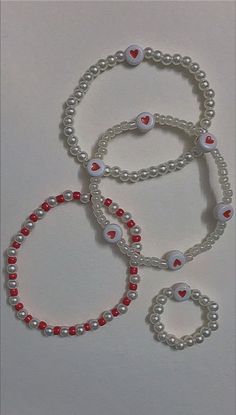 three bracelets with red and white beaded hearts on them, one in the shape of a heart