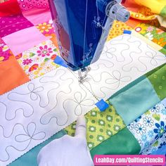 a close up of a sewing machine on top of a patchwork quilt with colorful fabrics