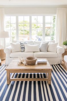 a living room with white furniture and blue striped rugs on the floor in front of large windows