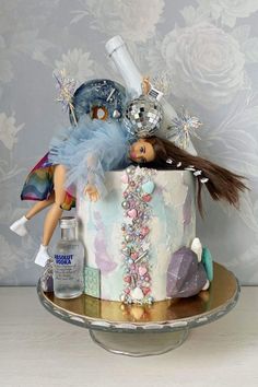 there is a cake that has been decorated with dolls and other items on top of it