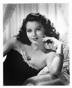 an old black and white photo of a woman with her hand on her chin, posing for the camera