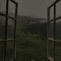 an open window with mountains in the background and foggy sky above it on a cloudy day