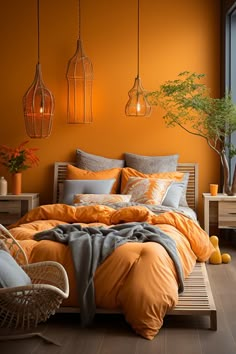 a bed with orange sheets and pillows in a room that has wooden flooring, two hanging lights above the bed