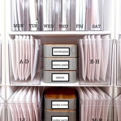 three bins with labels on them sitting in front of bookshelves and folders