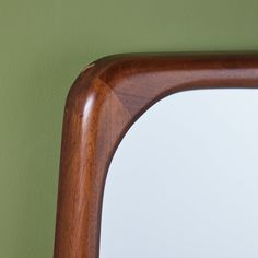 a wooden frame mirror against a green wall