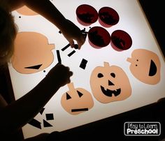 a person is cutting out pumpkins on a light box with cutouts to make them look like they have faces