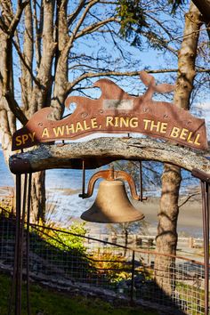 a sign that says, a whale ring the bell on it's side near some trees