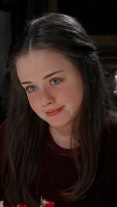 a girl with blue eyes holding a piece of cake in her hand and looking at the camera