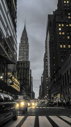 cars are driving down the street in front of tall buildings at night with lights on