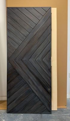 a large wooden door sitting inside of a room next to a white and tan wall