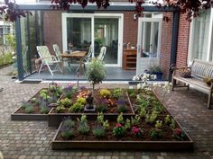 a patio area with brick pavers and flower beds in the center, surrounded by chairs