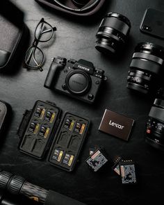 the contents of a camera and other accessories laid out on a black surface with glasses