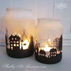 two glass jars with lit candles in them sitting on a white counter top next to each other