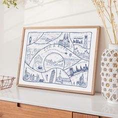 a blue and white map is hanging on the wall next to a vase with flowers