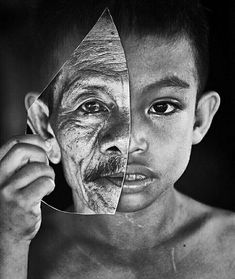 a young boy holding up a mirror to his face