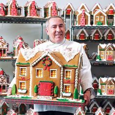 a man holding up a large gingerbread house