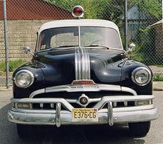 an old black and white car parked on the street