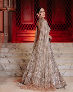 a woman in a gold and silver gown standing on steps with her back turned to the camera