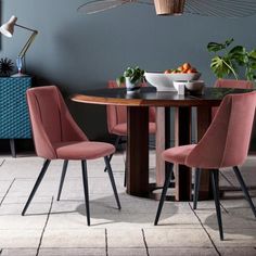 a dining room table with four chairs and a bowl of fruit on the table next to it