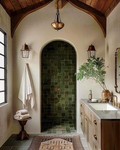 a bathroom with a green tile shower and white sink counter top next to a wooden door