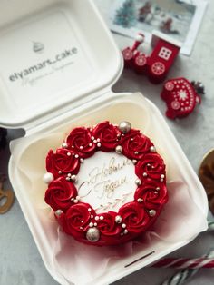 a heart shaped cake in a white box with red roses and pearls on it, surrounded by other holiday decorations