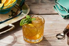 a glass filled with lemonade sitting on top of a wooden table next to plates and utensils