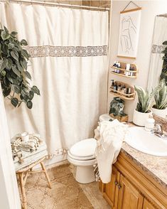 a bathroom with a white shower curtain next to a toilet and sink under a mirror