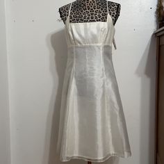 a white dress on a mannequin stand in front of a wall with a leopard print top