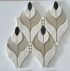 three white and black decorative tiles on a wall with one green leaf in the middle