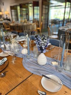 a wooden table topped with plates and vases filled with flowers on top of it