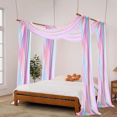 a bed with pink and blue drapes hanging over it