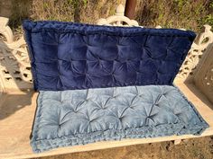 a blue velvet bench cushion sitting on top of a stone slab