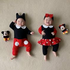 two babies dressed in mickey and minnie mouse costumes laying on the floor next to each other