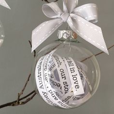 a christmas ornament hanging from a twig with a white ribbon and some words on it