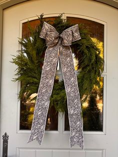 a wreath on the front door of a house with a bow hanging from it's side